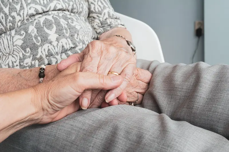 An older person holding hands with a family member