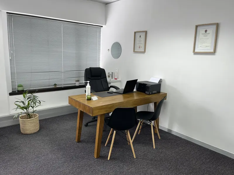 Dr Omar's consulting room with a desk, two chairs and framed certificates